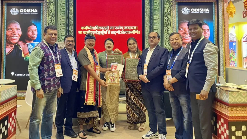Group photo at the Odisha tourism stand during ITB Asia 2026, with participants holding framed artworks